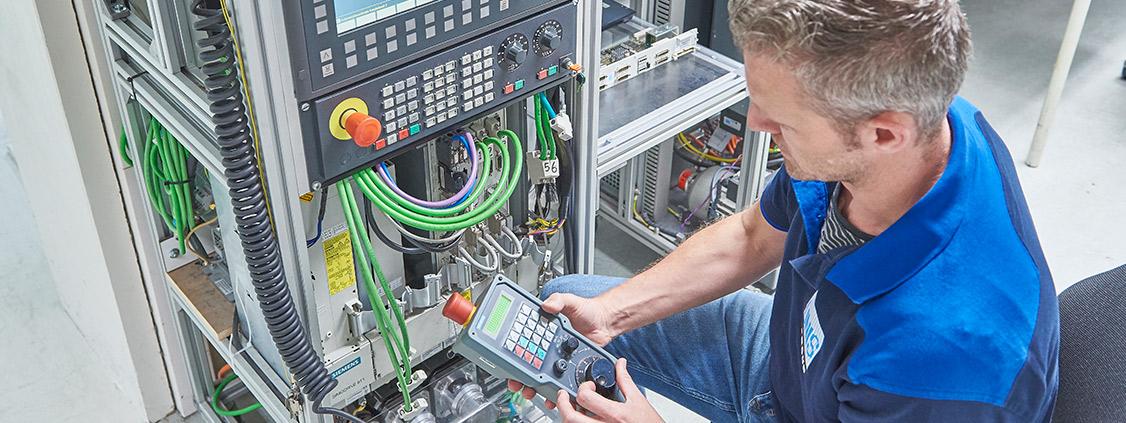 Technician inspecting and reconnecting cables inside an industrial